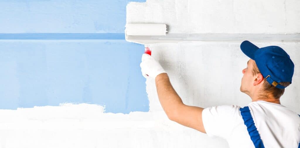 Man painting a wall to cover up normal wear and tear